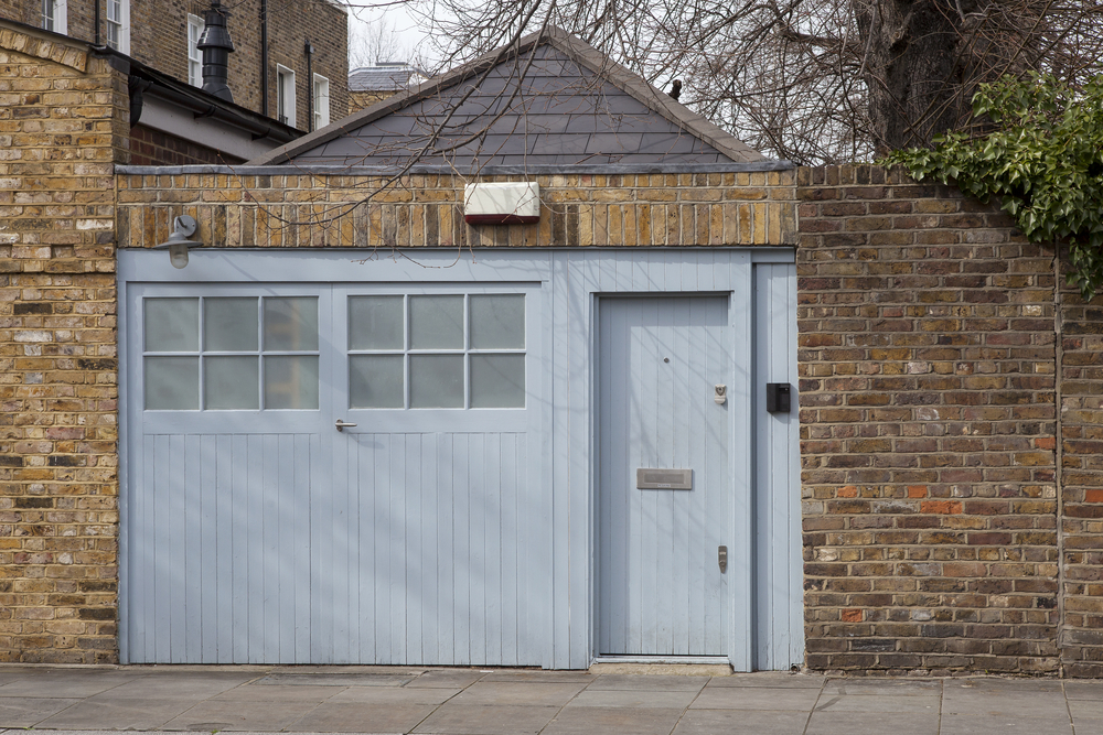 Traditional brick garage with blue timber door and side entrance, ideal for conversion into a home office or living space in 2025