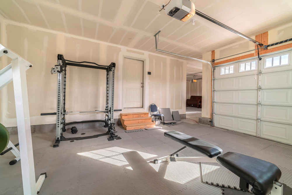Garage converted into a personal gym space with workout equipment, rubber flooring, and bright interior walls