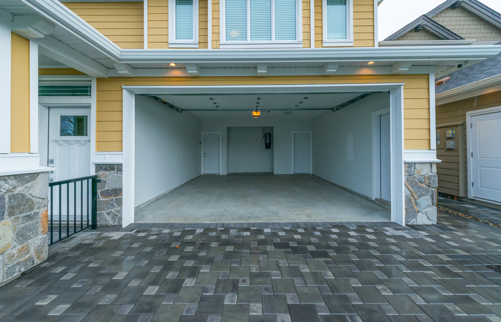 Exterior view of a clean, empty garage with open doors and paved driveway, ideal for a future home conversion