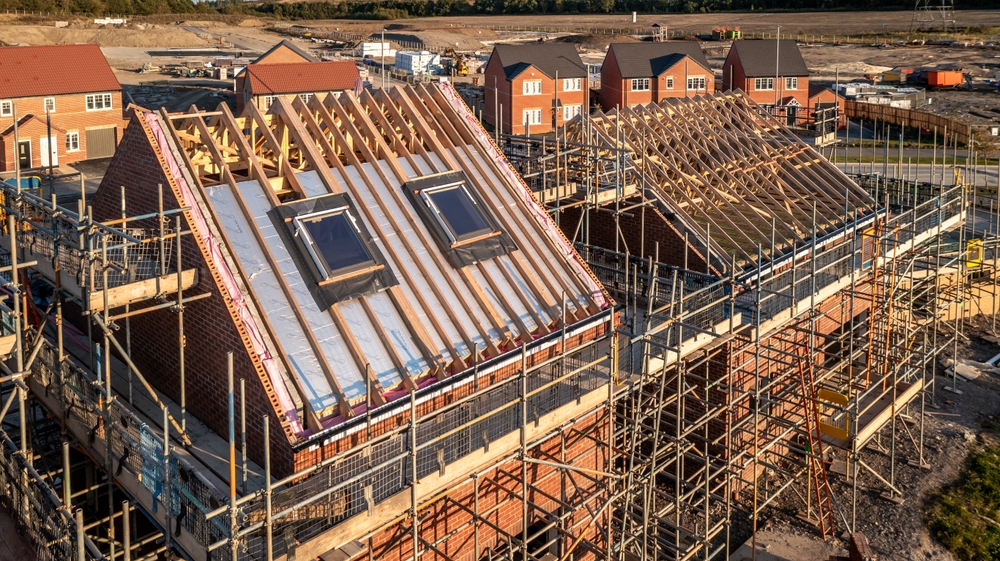 New-build homes in Horsham under construction with scaffolding, timber roof structures and partially completed roofing.