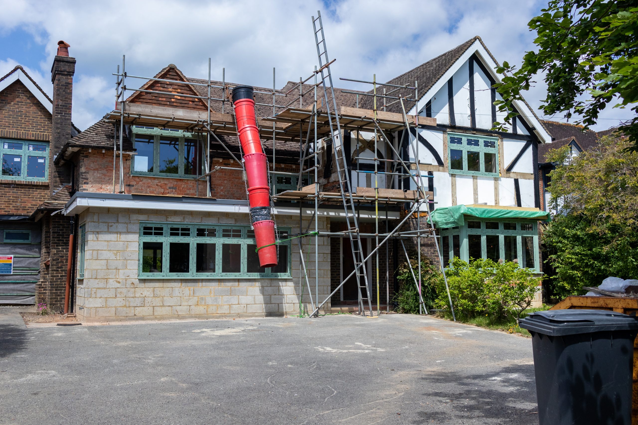 Large house undergoing a home extension with scaffolding, skip chute and new brickwork visible on the front elevation.